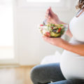 Schwangere Frau mit einer Salatschüssel in der Hand
