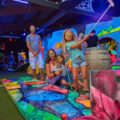 Kind schwingt Minigolfschläger in Neongolf