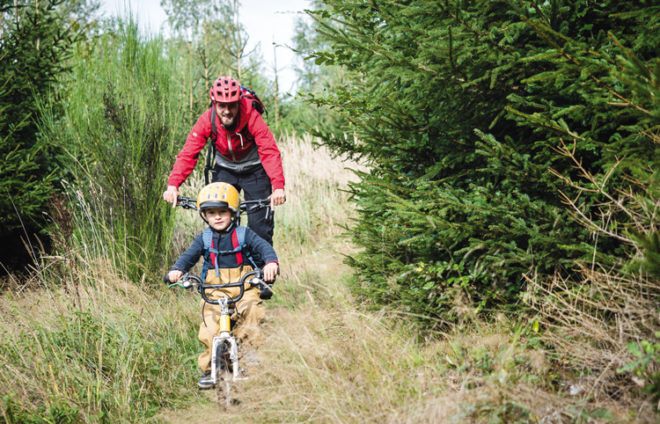 Vater und Kind im Wald mit dem Rad unterwegs