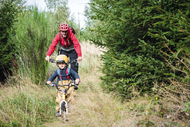 Vater und Kind im Wald mit dem Rad unterwegs