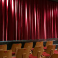 Leere Bühne mit rotem Vorhang und leeren Stuhlreihen