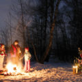 Eine Familie wärmt sich an einer Feuerstelle im Wald