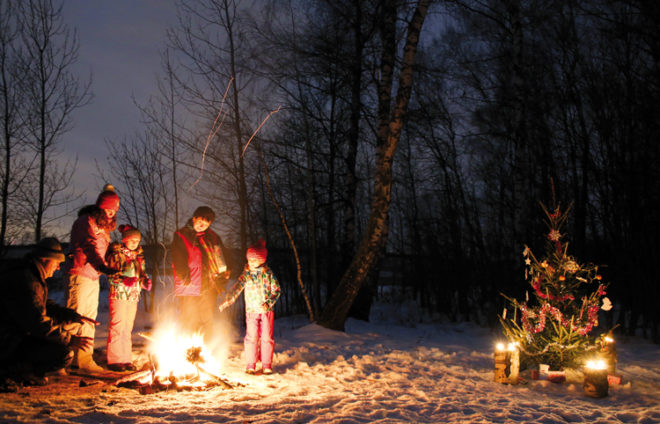 Eine Familie wärmt sich an einer Feuerstelle im Wald