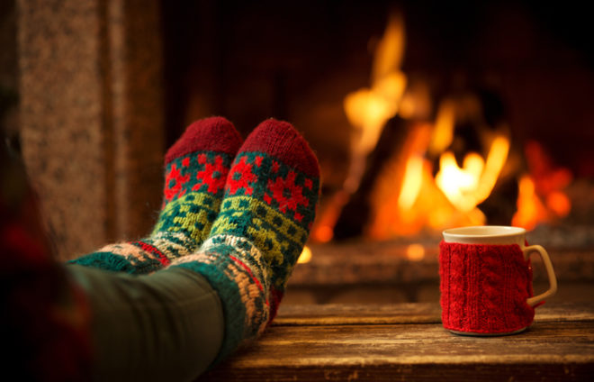 Füße in bunten Wollsocken auf einem Tisch vor einem Kamin