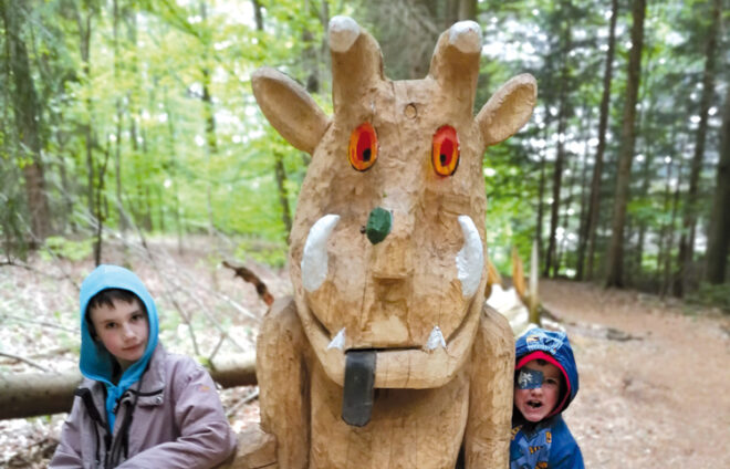 Kinder stehen an geschnitzter Figur von Grüffelo