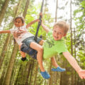 Kinder hängen am Seil im Wald