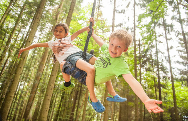 Kinder hängen am Seil im Wald