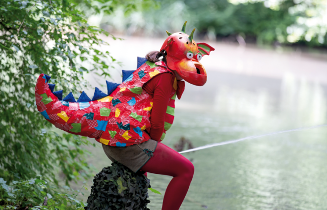 Kostümierter Drache auf einem Brunnen