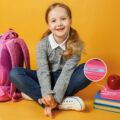 Mädchen mit Schulsachen vor orangenem Hintergrund