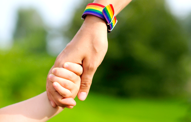 Hand mit Regenbogenarmband hält Kinderhand