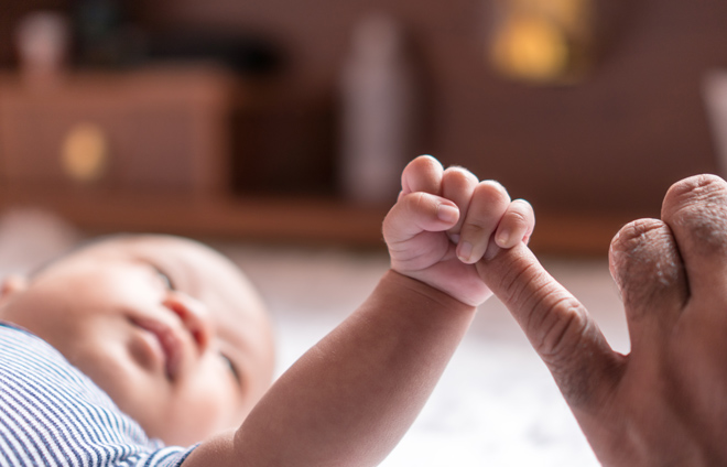 Baby greift einen erwachsenen Finger