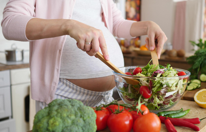 Schwangere Frau bereitet sich einen Salat zu